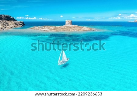 Beautiful seascape with white sailing yacht in summer on a sunny day aerial view. Popular beach La Pelosa, Sardinia, Italy. Travel, hobby concept