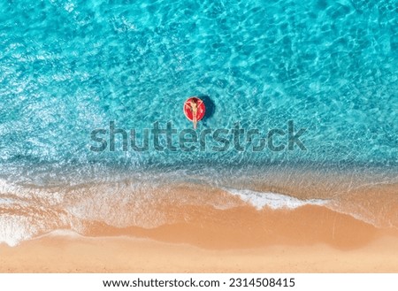 Beautiful seascape with woman with red swim ring in blue sea at sunset in summer. Aewrial view. Tropical scenery with girl, clear water, waves, sandy beach. Top view. Vacation. Sardinia island, Italy	