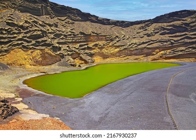 Beautiful secluded lagoon valley, red rocks, deep green lake (Lago verde), black lava sand, impressive rugged sharp steep cliffs - El Golfo, Lanzarote 