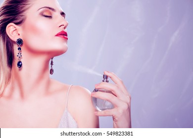 Beautiful seductive woman holding a perfume bottle and applying it