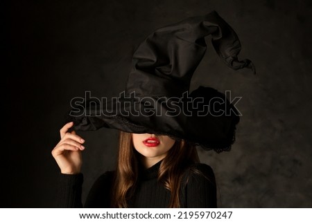 Beautiful seductive young girl with red lipstick in witch hat