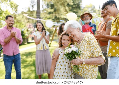 Beautiful senior birthday woman receiving flowers from granddaughter. - Powered by Shutterstock