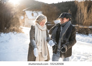 Beautiful Senior Couple Blowing Snow In Sunny Winter Nature