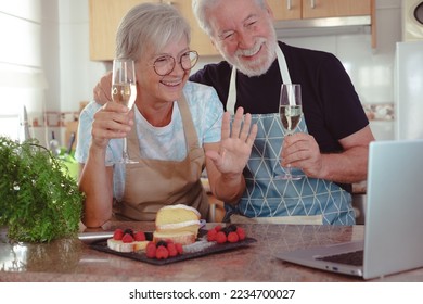 Beautiful senior couple in the home kitchen after baking their homemade plumcake they hold two glasses of wine while chatting with friends or family on the computer. Cooking at home together - Powered by Shutterstock