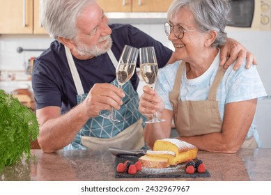 Beautiful senior couple in the home kitchen holding a glass of wine toasting and smiling - Powered by Shutterstock