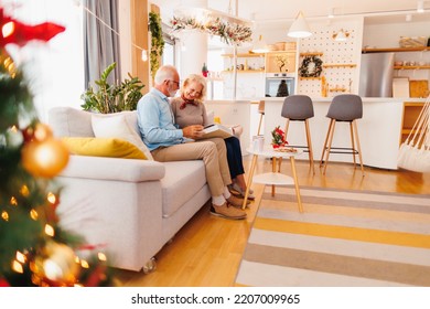 Beautiful Senior Couple In Love Spending Christmas Day Together At Home, Leafing Through An Old Photo Album