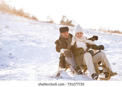 Beautiful Senior Couple On Sledge Having Fun, Winter Day.