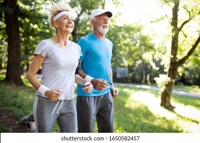 Beautiful Senior Couple Running Outside In Forest