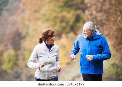 Beautiful Senior Couple Running Outside In Sunny Autumn Nature