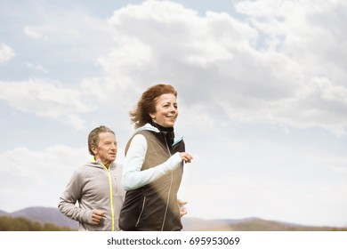 Beautiful Senior Couple Running Outside On Green Hills.