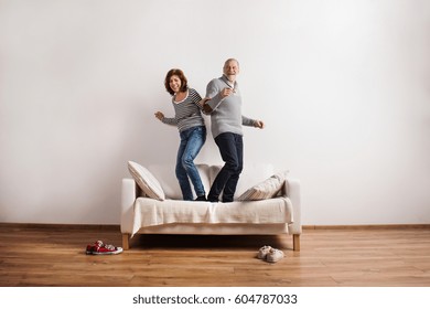 Beautiful Senior Couple Standing On Couch, Dancing. Studio Shot.