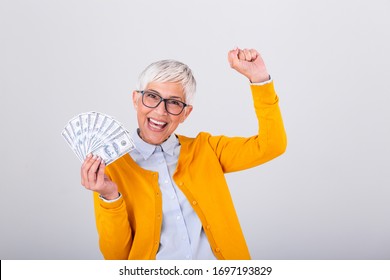 Beautiful senior lady holding a bunch of $100 bills with surprised facial expression. Mature woman winning money. Finances and people concept, senior woman holding hundreds of dollar money banknotes