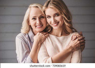 Beautiful senior mom and her adult daughter are hugging, looking at camera and smiling - Shutterstock ID 739083619