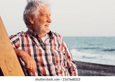 Beautiful senior white haired man on the beach looking at the golden hour of sunset at sea enjoying free time, vacation or retirement - Powered by Shutterstock