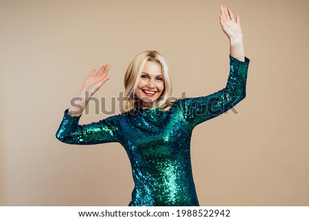 Beautiful senior woman dancing and making party. Middle aged person wearing a sequins green dress