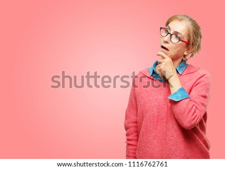Beautiful senior woman with a goofy, dumb, silly look, feeling shocked and confused at a recent realization, not really understanding an idea.