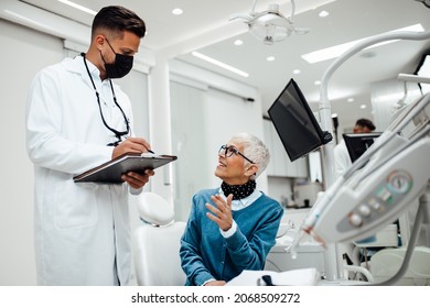 Beautiful Senior Woman Having Dental Treatment At Dentist's Office. Dentist Is Wearing Protective Face Mask Due To Coronavirus Pandemic.	