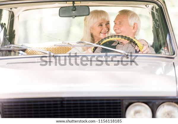 beautiful senior
woman hugging man in vintage
car