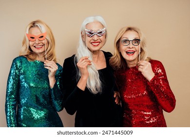 Beautiful senior woman making party and celebrating new year. Middle aged women wearing elegant glittering dresses and having fun. Studio portraits on colored background - Powered by Shutterstock