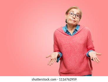 Beautiful senior woman with a quizzical and confused look, doubting between different choices or possibilities with a wondering expression, comparing and posing a question.