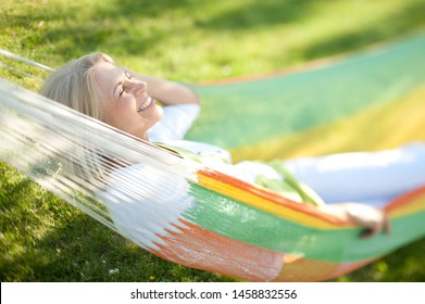 Beautiful senior woman relaxing in the garden in the hammock - Powered by Shutterstock