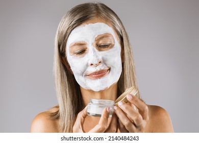 Beautiful Senior Woman Using Organic Cosmetic Mask For Moisturizing Facial Skin. Isolated Over Grey Studio Background. Cosmetology Concept.