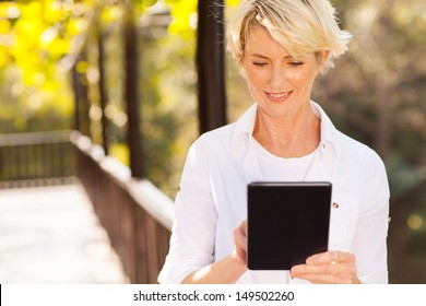 Beautiful Senior Woman Using Tablet Computer Outdoors