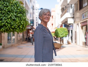 Beautiful senior woman walking down in city street. Elderly white haired lady dressed in fashion enjoying shopping - Powered by Shutterstock