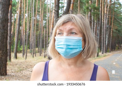 Beautiful Senior Woman Wearing A Medical Mask Running Outdoors In The Park On A Treadmill. Feeling Happy With Nature Background, Health Of The Elderly. Enjoying A Summer Day, Healthy Concept