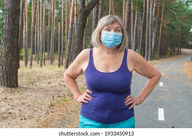 Beautiful Senior Woman Wearing A Medical Mask Running Outdoors In The Park On A Treadmill. Feeling Happy With Nature Background, Health Of The Elderly. Enjoying A Summer Day, Healthy Concept