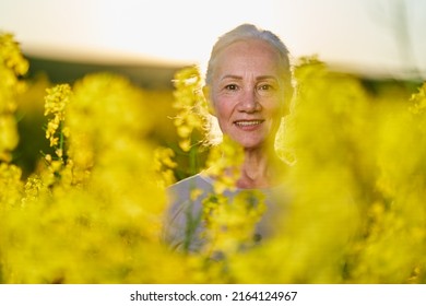 Beautiful senior woman with white hair in a canola field