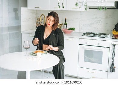 Beautiful Sensual Brunette Young Woman Plus Size Body Positive With Dish Of Pasta And Glass Of Wine On Kitchen At Home