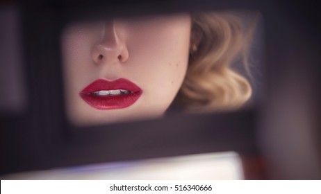 Beautiful Sensual Caucasian Woman With Exotic Appearance With Curled Blonde Hairstyle And Red Lips, Looking Sideways On A Rearview Mirror In The Car. Close Up Of Lips