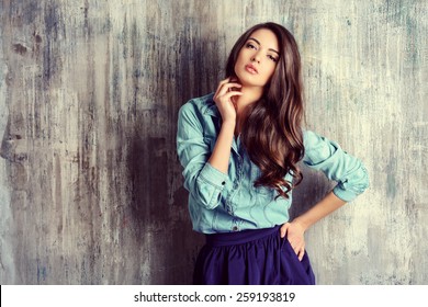 Beautiful Sensual Woman In Jeans Clothes Stands By The Grunge Wall. Fashion.