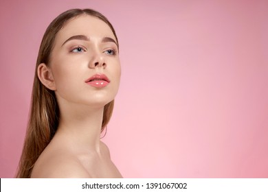 Beautiful, sensual, young model with plump lips and natural make up posing on pink background. Sexy, fashionable, attractive girl with naked shoulders and smooth skin.