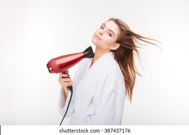 Beautiful sensual young woman in bathrobe  drying her hair with dryer over white background