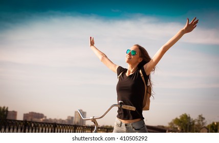 Beautiful Sensuality Elegance Brown Hair Woman Cyclist, Has Happy Fun Cheerful Smiling Face, Black T-shirt, Blue Jeans. Has Slim Sport Body. Motion On Great Bike In Urban City. Portrait Nature. Quest