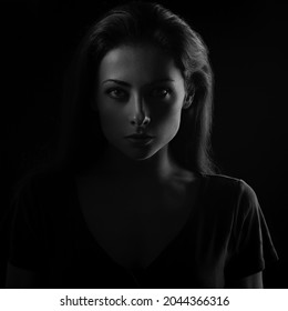 Beautiful Serious Mysterious Woman In Darkness Looking Dramatic. Closeup Portrait In Dark Shadow Low Key. Art.  Closeup Front Face View On Black Background. Black And White