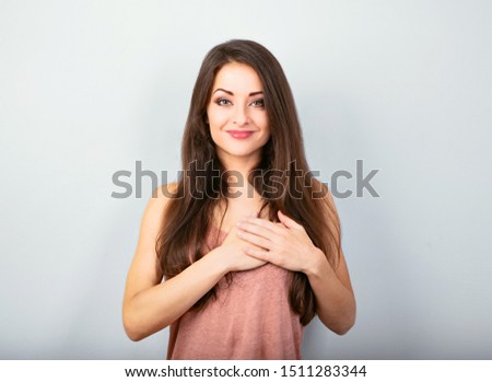 Beautiful serious woman  in love holding herself chest and heart two hands with enjoying smiling face and thinking about emotion relationship. portrait