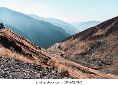 The Beautiful Serpentine Transfagarasan Road,a Mountain Area In Romania On A Sunny Morning. The Valley Creates A V Shape. Different Tipes Of Rocks, Vegetation, Reed,outline Of The Mountains.