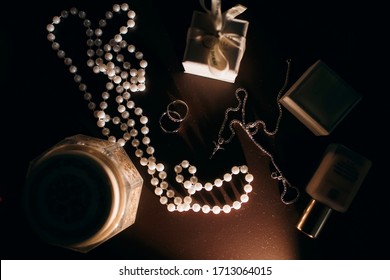 Beautiful set of women's wedding accessories. Morning bride pearl ring, earrings, perfume and wedding rings on a dark background.
