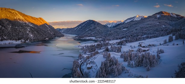 The beautiful setting of the Weissensee Nature Park. Frozen Lake Weissensee, Carinthia, Alps, Austria. Aerial drone shot in January 2022. Sunset time. - Powered by Shutterstock