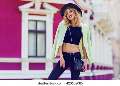 Beautiful sexy blonde girl in casual clothes with perfect  figure  walking around the city. Fashion and city style. Black stylish hat,  short top. Sensual full lips.