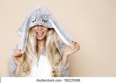 Beautiful Sexy Blonde Woman Wearing A Pajama, A Bunny Costume, Smiling Happily. Fashion Model On A Beige Background In  Easter Bunny Costume.