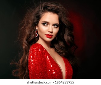 Beautiful sexy brunette in red dress with healthy curly hair and glamour makeup. Fashion Beauty Girl Isolated on black studio Background. 
