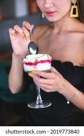 Beautiful Sexy Brunette Woman In Restaurant Or Cafe With Ice Cream Tiramisu Dessert. Fashion Photo Of Young Woman In Black Dress With Hairstyle And Makeup, Eating Dessert. Eat Out Concept.