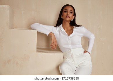Beautiful sexy brunette woman tanned skin face cosmetic makeup wear white suit pants for date walk office fashion clothes style collection interior room  sand color safari summer casual.