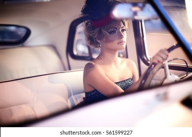 beautiful sexy fashion blond girl model with bright makeup and curly hairstyle in retro style sitting in old car