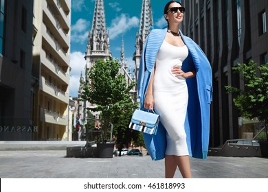 Beautiful Sexy Fashion Stylish Female Model Long Dark Hair Wearing Natural Make-up In Chic Slinky Dress Knit Long Coat Jacket Accessory Sunglasses Bag Shoes Jewelry Vintage City Church Modern Building