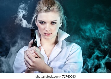 Beautiful Sexy Girl Holding Gun. Smoke Background